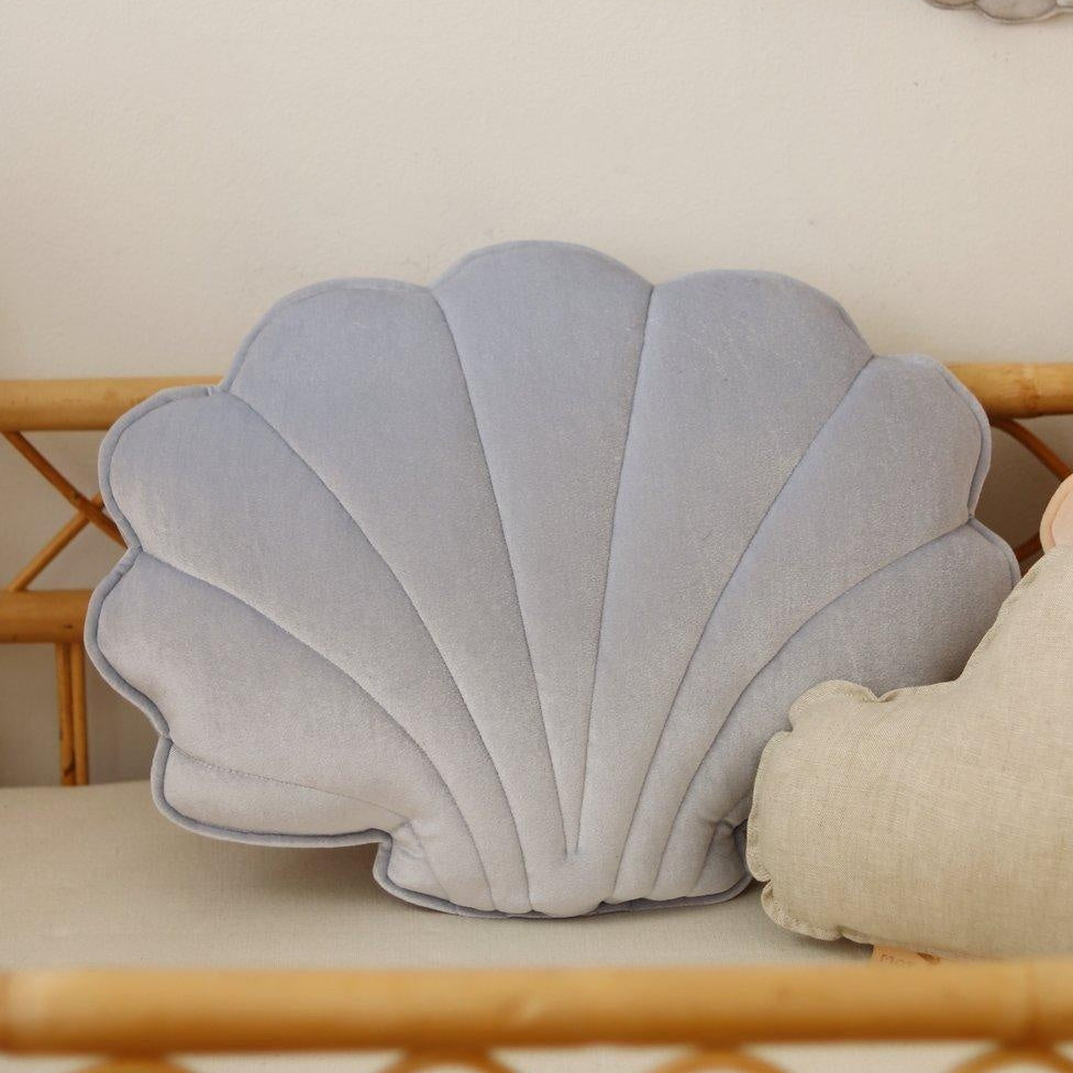 Shell-shaped pillow and decorative shell garland on a light-colored wall.
