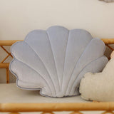 Shell-shaped pillow and decorative shell garland on a light-colored wall.