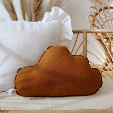 Brown cushion on a wicker chair with white pillows and decorative elements in the background