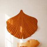 Decorative shell-shaped pillows on a wooden floor against a white wall