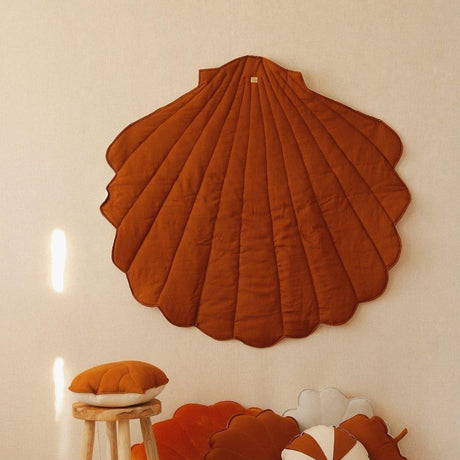 Decorative shell wall art and cushions in a room setting.