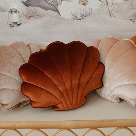 Shell-shaped pillow on a decorative shelf with an underwater-themed wall mural in the background.