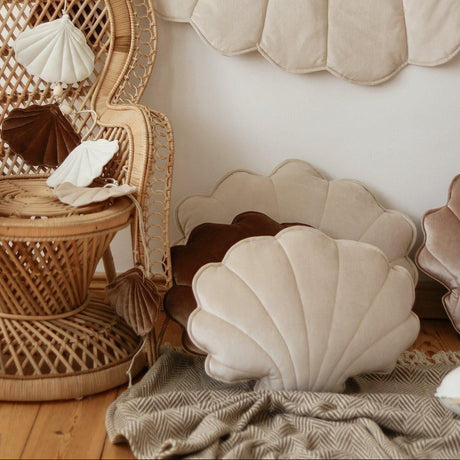 Decorative shell pillows and a wicker chair in a cozy room setting.