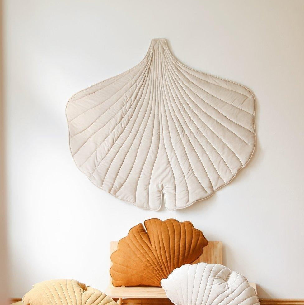 Shell-shaped decorative pillows on a wooden floor against a white wall