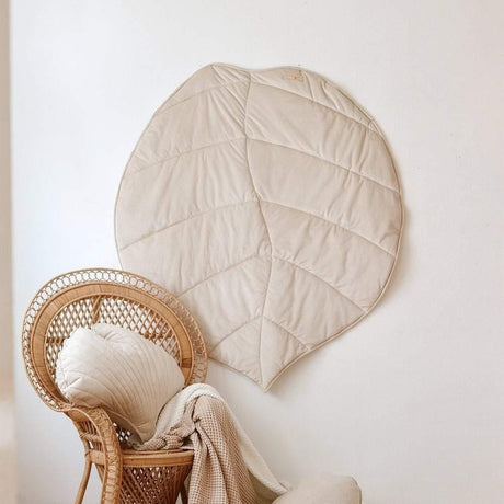 Wicker chair with a round beige cushion against a white wall