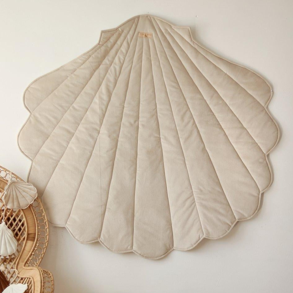 Shell-shaped cushions on a wooden floor against a white wall