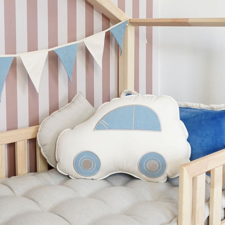 Car-shaped pillow in a crib with striped wall and flag banner