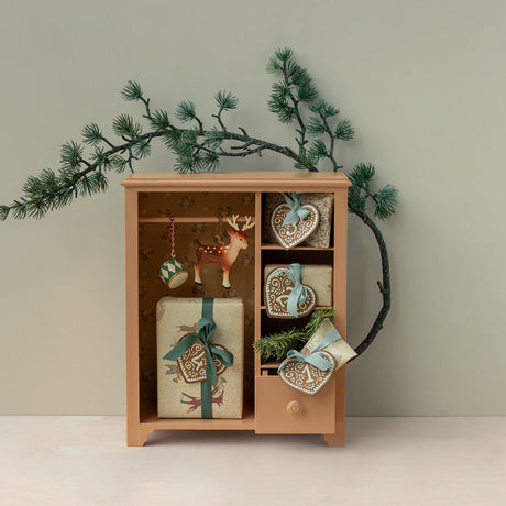 Wooden cabinet with decorative items and Christmas decorations on a light background