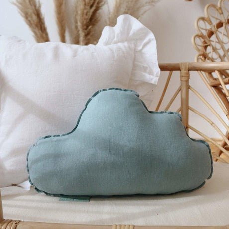 Blue cloud-shaped pillow on a white surface with a neutral background