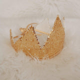 Gold tiara with beaded details on a textured white surface