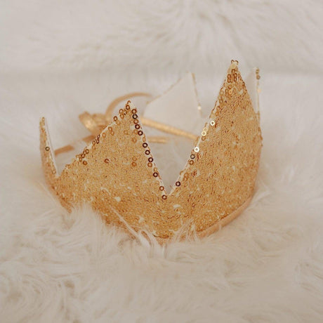 Gold tiara with beaded details on a textured white surface