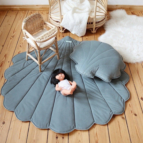 Round gray rug on a wooden floor with a wicker chair and decorative elements.