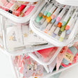 Clear plastic containers filled with colorful stationery items on a white surface