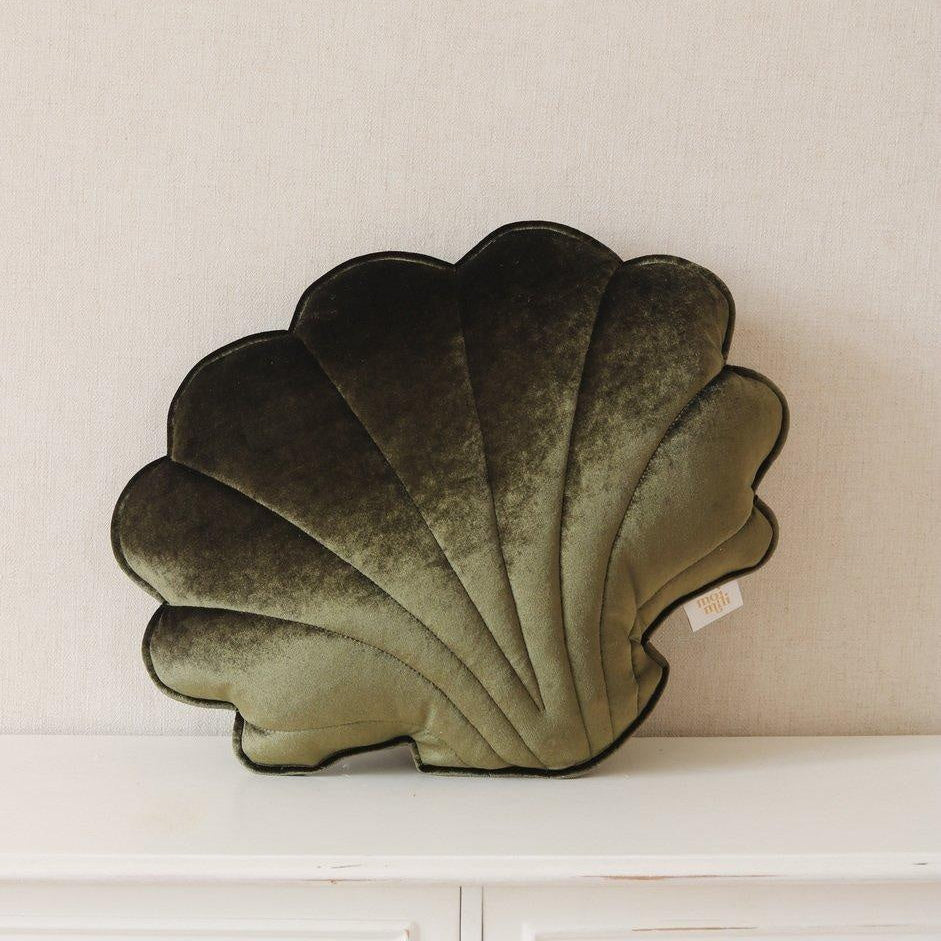 Decorative shell-shaped pillow on a white surface with a neutral background
