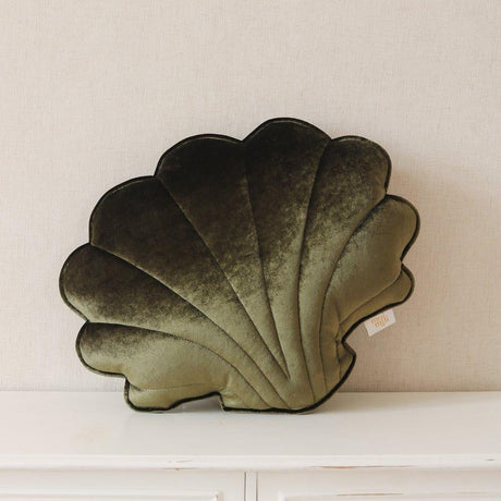 Decorative shell-shaped pillow on a white surface with a neutral background