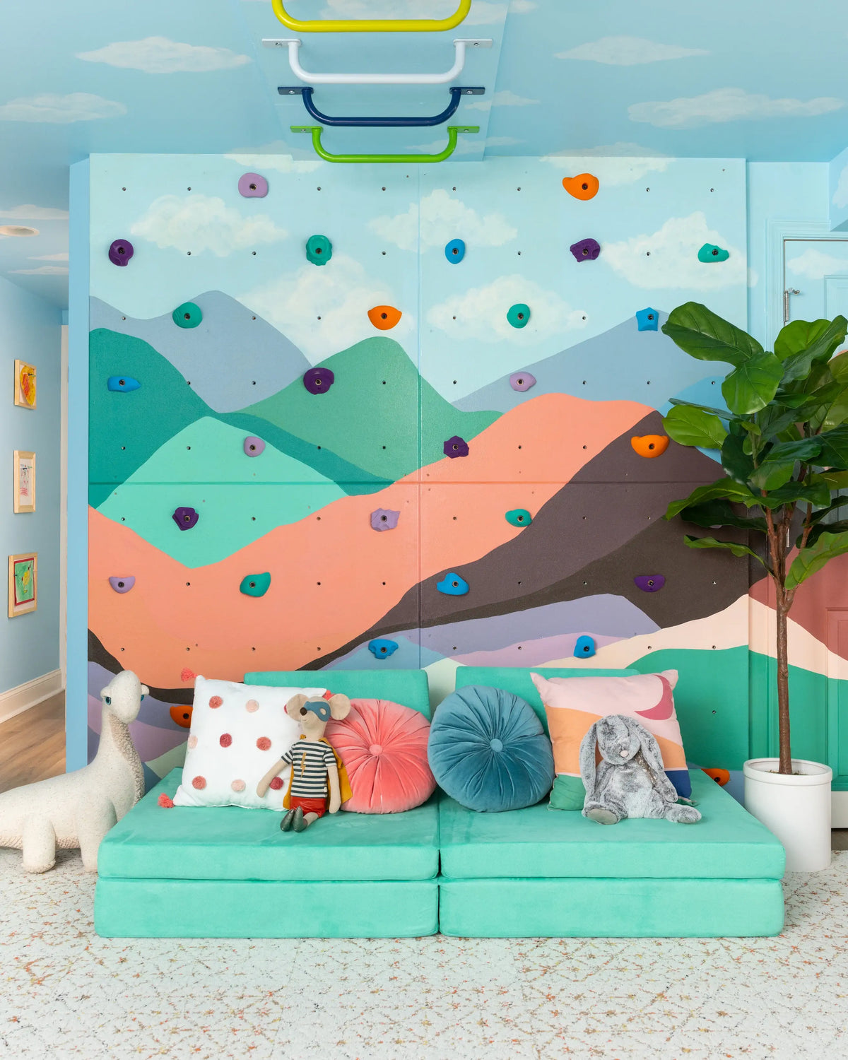 Children’s rock wall set against a mountain mural with foam cubes for safe landings.