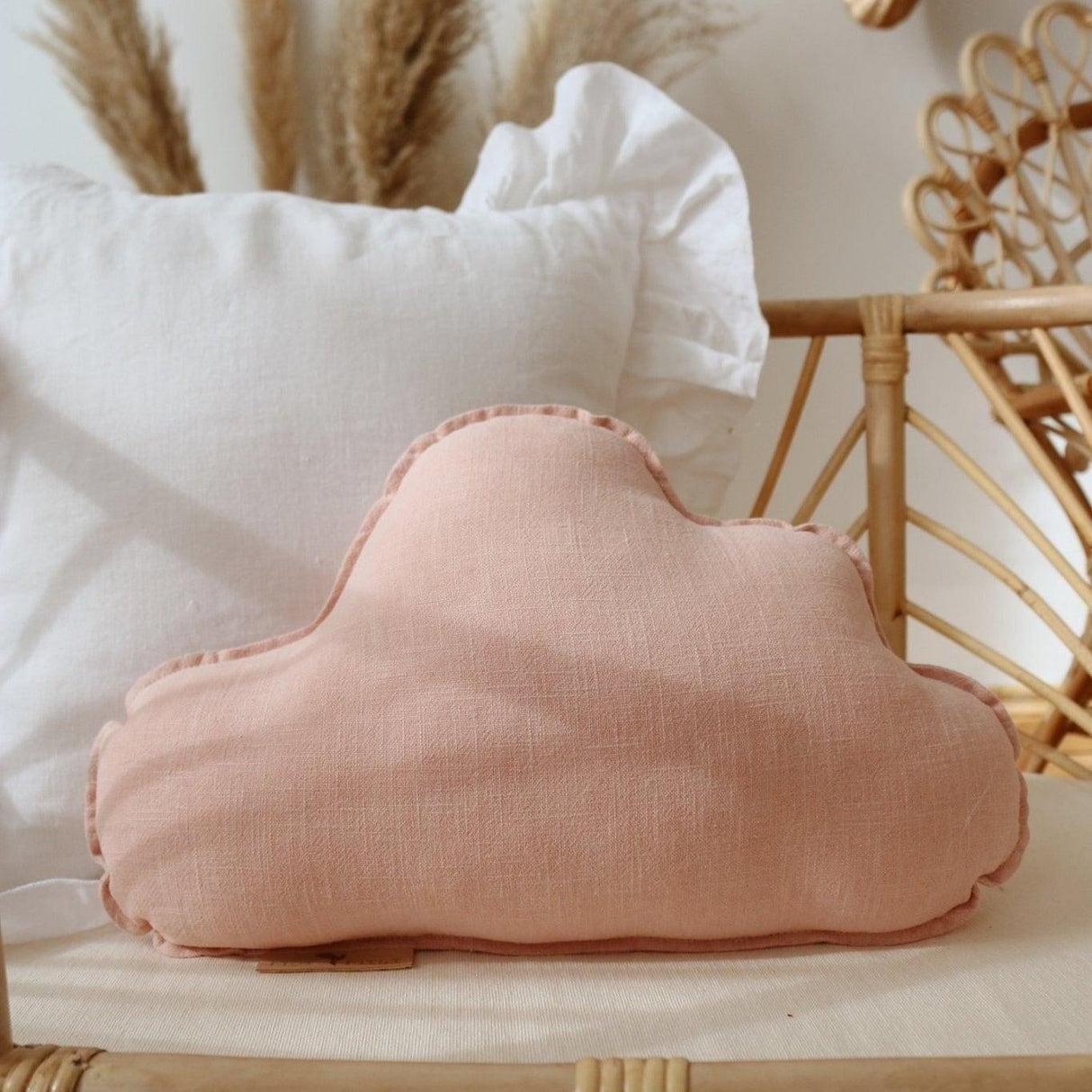 Pink cloud cushion on a wicker table with decorative elements in the background