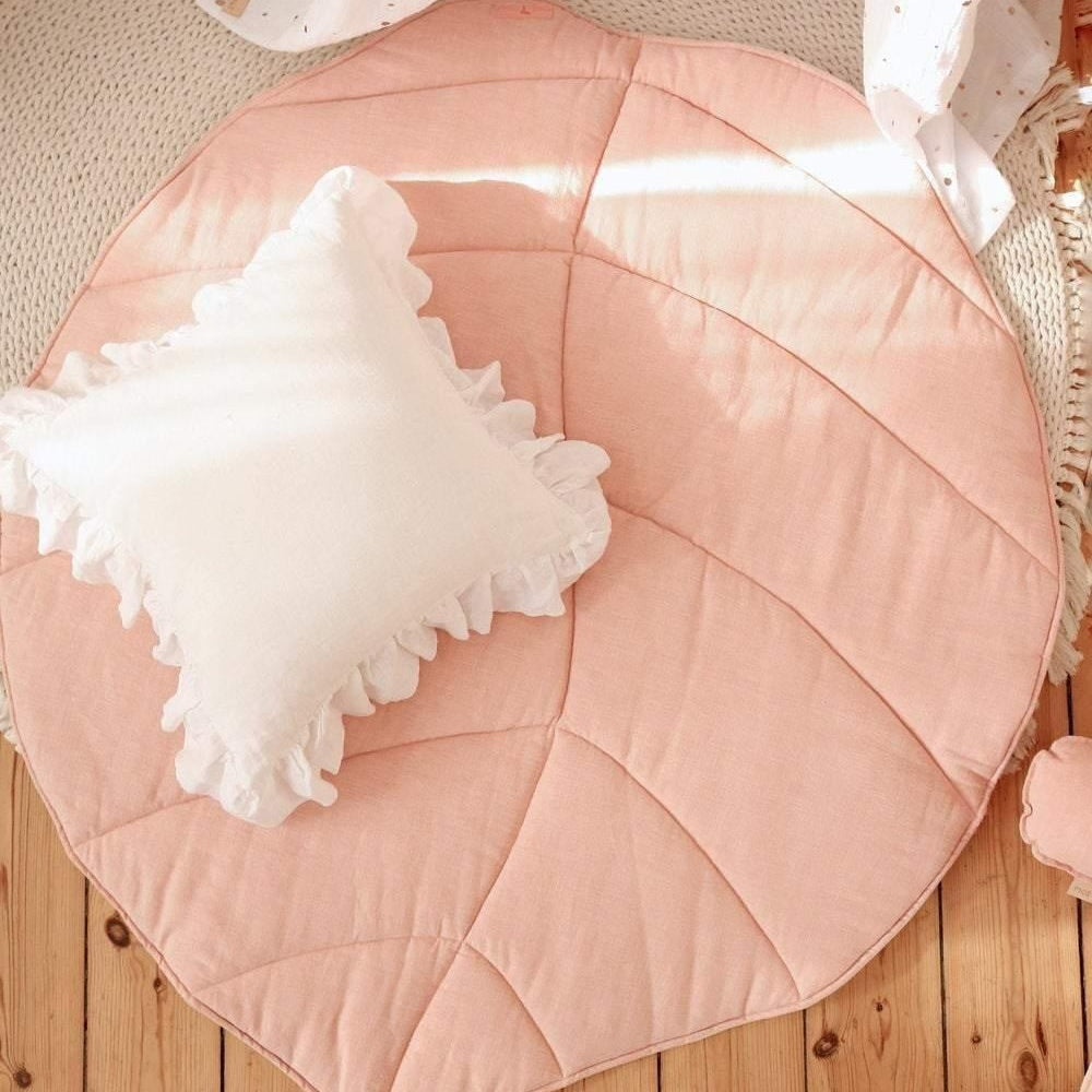Leaf-shaped pink cushion with a white decorative pillow on a wooden floor.