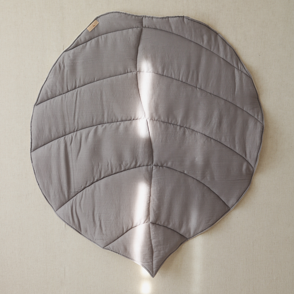 Gray leaf-shaped cushion on a beige wall
