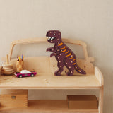 Wooden toy car with a dinosaur figure on top against a plain wall.