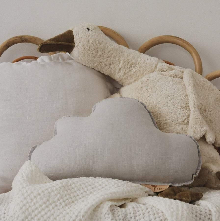 Cozy bedroom scene with a cloud-shaped pillow, soft blanket, and plush toy on a bed.
