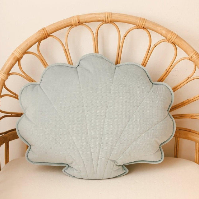 Shell-shaped pillow on a wicker chair with a beige background