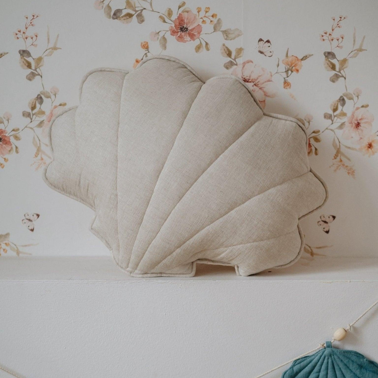 Decorative shell-shaped pillows and a banner on a floral background