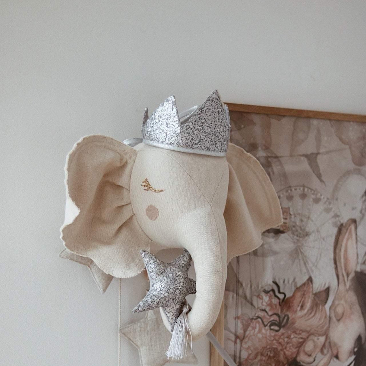 Decorative elephant head with a silver crown and star-shaped ornaments on a wall.