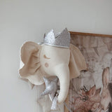 Decorative elephant head with a silver crown and star-shaped ornaments on a wall.