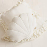 White pillow with ruffled edges on a light wooden surface